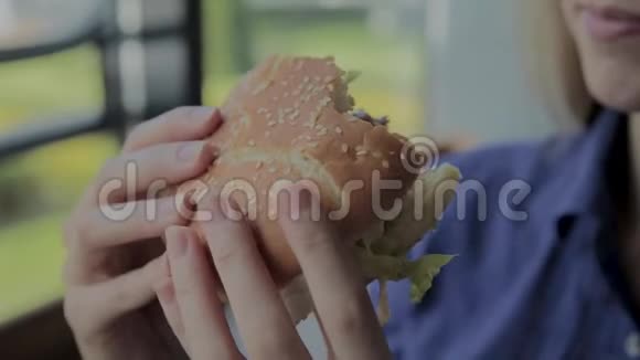 漂亮的女孩吃汉堡快餐店视频的预览图