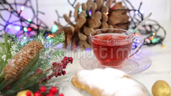 一杯带蜂蜜和牛角面包的茶雪中圣诞树的一根树枝圣诞灯视频的预览图