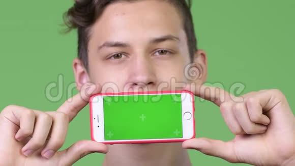 年轻英俊的十几岁男孩带着电话视频的预览图