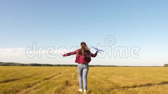 青少年梦想飞行和成为飞行员快乐的女孩带着玩具飞机在夕阳下的田野上奔跑视频的预览图