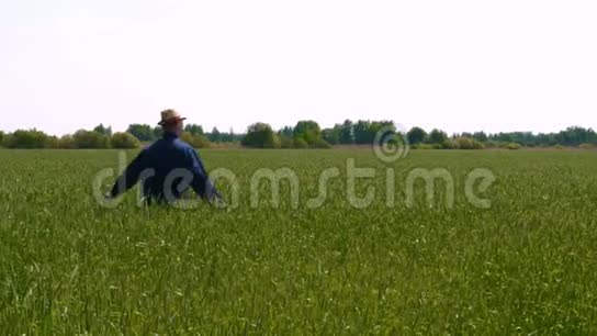 一个穿着制服戴着草帽的年轻人在田野中间的画像视频的预览图