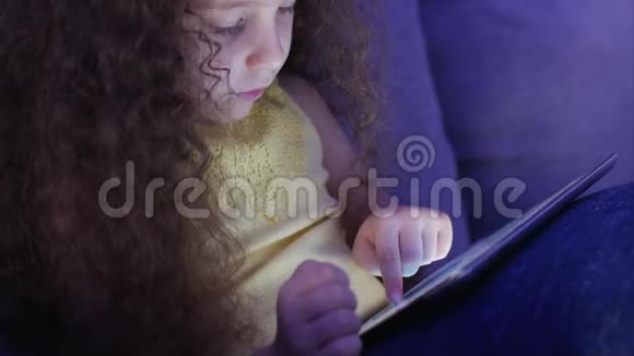可爱的小女孩花了闲暇时间玩手机游戏并打破明亮的屏幕与她的手概念视频的预览图