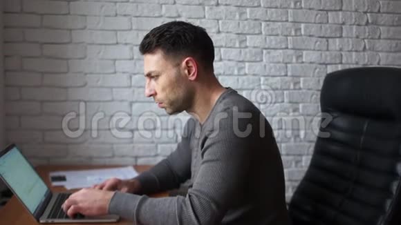 年轻的黑发程序员设计师工作与笔记本电脑男人专注而集中时间管理在视频的预览图