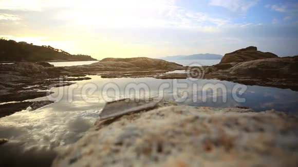 女人走在夕阳下的岩石海滩在海里苏视频的预览图