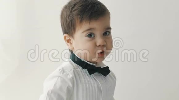 穿着蝴蝶结的小可爱男孩微笑着做着滑稽的脸时髦的休闲孩子视频的预览图