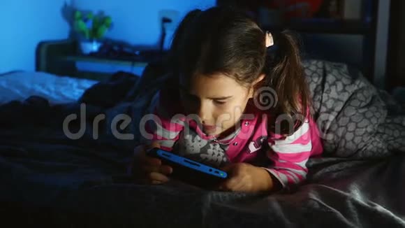 晚上在室内玩便携式电子游戏机的少女视频的预览图