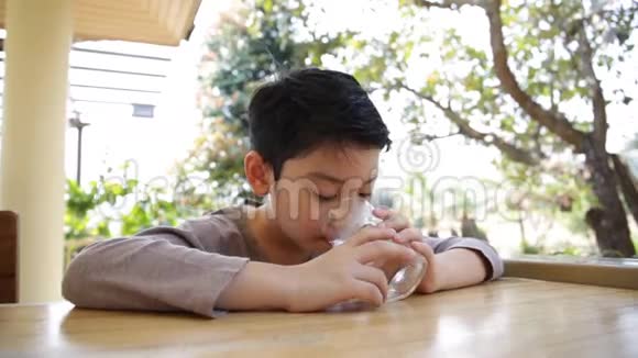 年轻的亚洲孩子喝一杯水视频的预览图