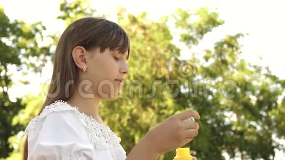 美丽的女孩在春天夏天和微笑的公园里吹肥皂泡慢动作年轻女孩在玩视频的预览图