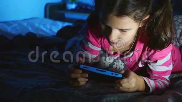晚上在室内玩便携式电子游戏机的少年女孩视频的预览图