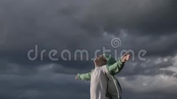 快乐的男孩举起双手仰望天空看着太阳刮风的天气视频的预览图
