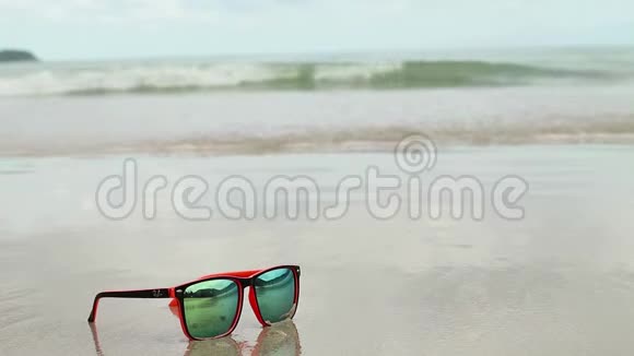 太阳眼镜躺在沙滩上戴着墨镜反射着大海海浪和天空视频的预览图