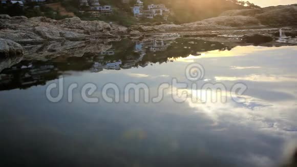 女人走在夕阳下的岩石海滩在海里苏视频的预览图