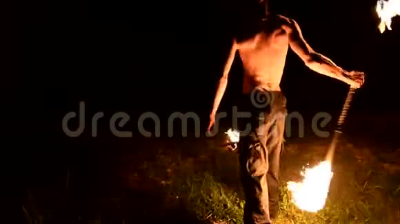 低调年轻男性长头发裸露的躯干在黑色的夜间视频中旋转燃烧的火炬视频的预览图