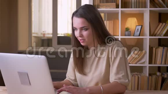 一位年轻漂亮的白种人女商人在办公室室内的笔记本电脑上打字的特写照片视频的预览图