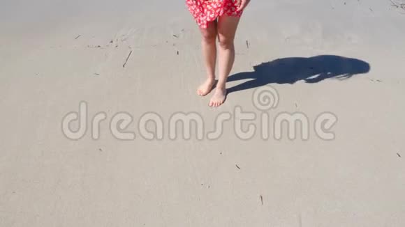 年轻的女人穿着红色的裙子在沙滩上画着一颗心海滩的心脏图视频的预览图