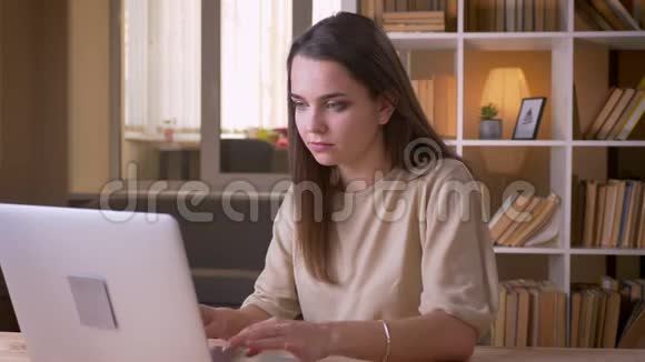 在办公室内使用笔记本电脑的年轻有魅力的高加索女商人的特写肖像视频的预览图