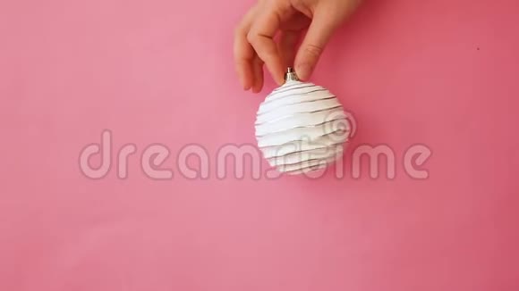 简单的最小设计女性手拿圣诞装饰球隔离粉红色粉彩色彩时髦视频的预览图