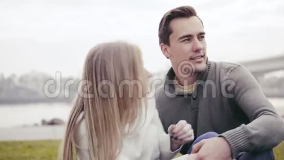 恋爱中的情侣坐在草地上拥抱在公园里视频的预览图
