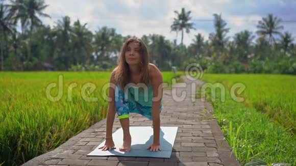 一位年轻女子在美丽的稻田里练习瑜伽的慢镜头视频的预览图