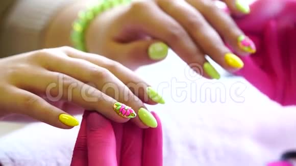 美容师在美甲沙龙中将指甲油涂在女性指甲上的特写镜头一只黄色的女人的手视频的预览图