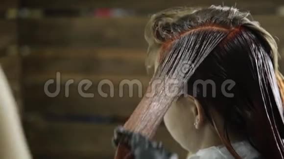 理发师为年轻女人做染发美发人的观念视频的预览图