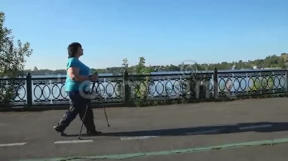 在一个阳光明媚的夏日早晨一个女人用棍子穿过公园视频的预览图