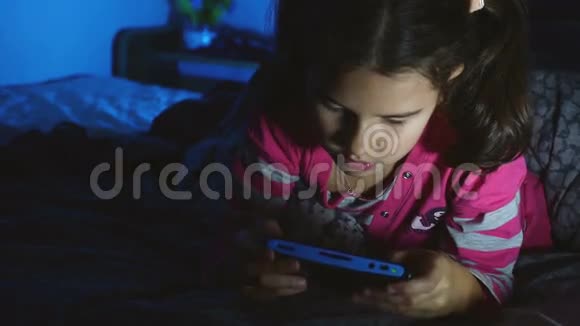 晚上在室内玩便携式电子游戏机的少女视频的预览图