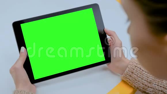 女人看着家里有绿色屏幕的平板电脑视频的预览图