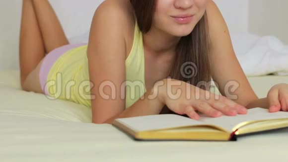 美丽的女孩躺在床上看书视频的预览图