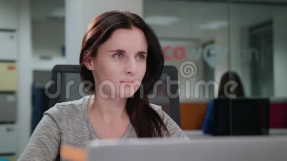 一位女士坐在办公室的笔记本电脑前视频的预览图