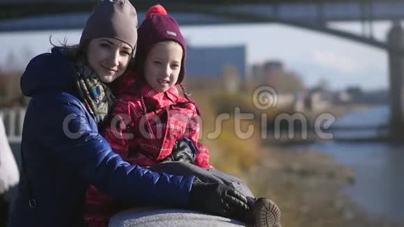 一家人在城市河堤上的年轻母亲和小女儿慢动作视频的预览图