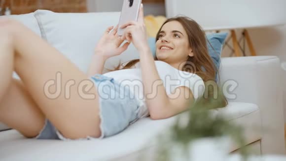 年轻女子在家里使用智能手机视频的预览图