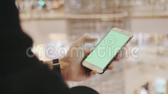 男性手使用智能手机与绿色屏幕在购物中心背景节日装饰品视频的预览图