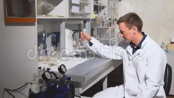 年轻的科学家在实验室里用液体进行化学实验视频的预览图