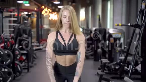 年轻漂亮的女子在健身房做有重量的运动视频的预览图