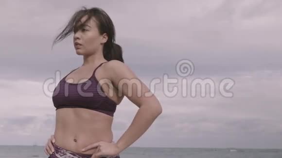 少妇在多云天气下在海滩上工作伸展健身慢动作视频的预览图