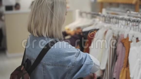 购物女孩服装店里一个漂亮女人的肖像一个年轻的金发女孩红唇在服装店视频的预览图