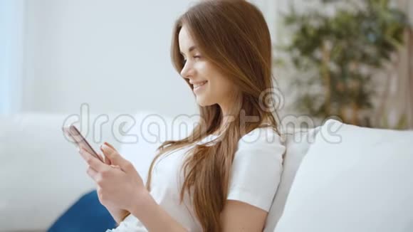 年轻女子在家里使用智能手机视频的预览图