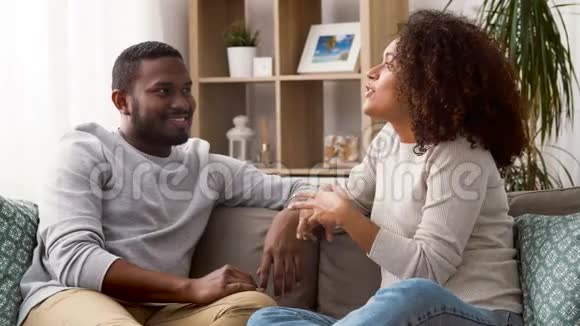 快乐的一对夫妇坐在沙发上在家里聊天视频的预览图
