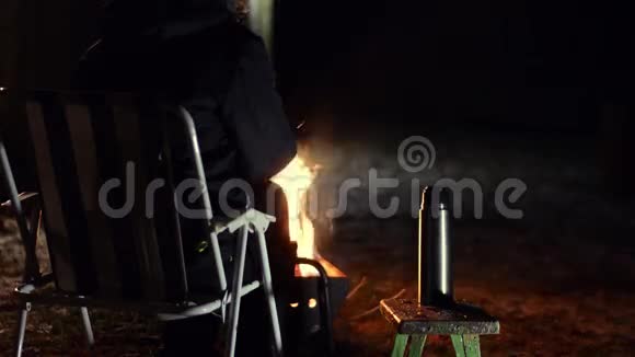 坐在篝火前端着一杯茶的女人视频的预览图