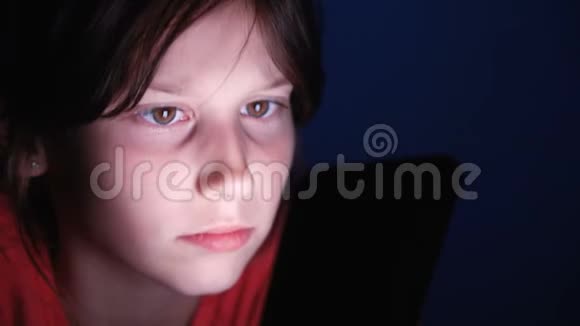 白种人女孩在床上玩平板电脑在深蓝色的灯光下黑色视频的预览图
