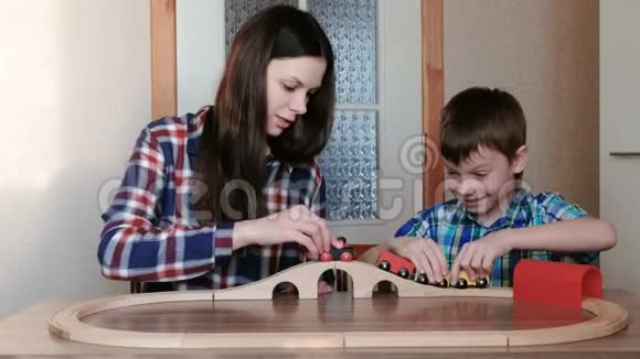 一起玩妈妈和儿子正在玩一条木制铁路坐在桌子旁的火车马车和隧道视频的预览图