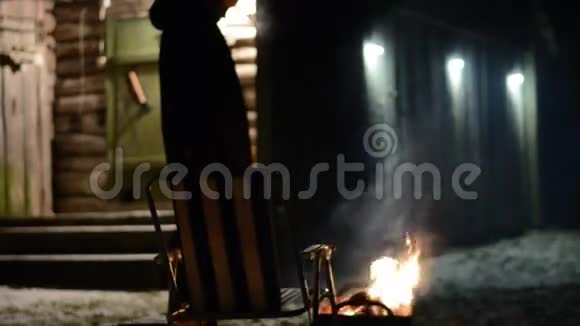 坐在篝火前端着一杯茶的女人视频的预览图