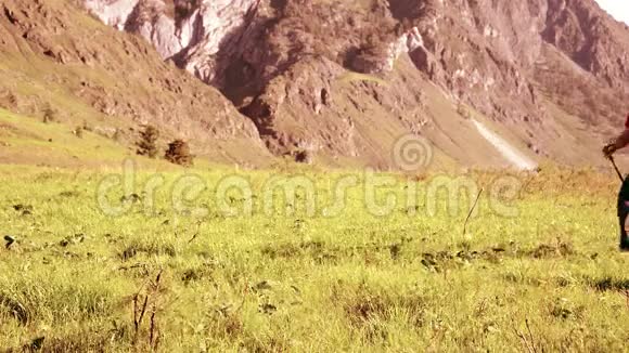 徒步旅行者带着背包在绿色的山地草地上行走夏季运动和娱乐理念视频的预览图