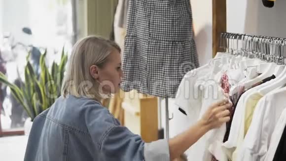 购物女孩服装店里一个漂亮女人的肖像一个年轻的金发女孩红唇在服装店视频的预览图
