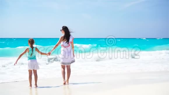 在热带海滩上可爱的小女孩和年轻的母亲家庭在加勒比海度假享受海景视频的预览图