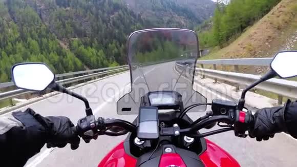 骑摩托车的摩托车骑在瑞士阿尔卑斯山附近美丽的风景山路上视频的预览图