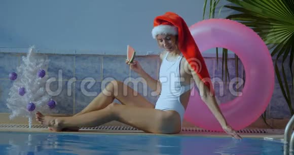 游泳池边戴圣诞帽的漂亮年轻女子视频的预览图