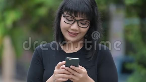 美丽快乐的亚洲女商人在户外大街上用电话视频的预览图