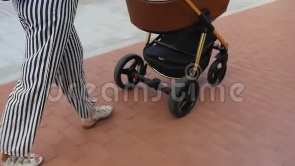 妈妈带着婴儿车在长廊散步家庭母性和人的概念有婴儿的幸福母亲视频的预览图